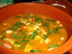 a bowl filled with soup sitting on top of a stove next to a potted plant