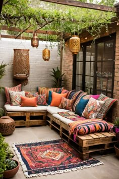 an outdoor seating area with lots of pillows and rugs