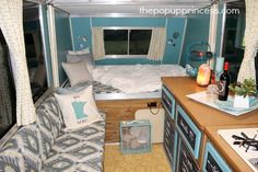 the interior of a camper with blue walls and white curtains