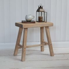 a small wooden table with a tea pot on it and a lantern next to it