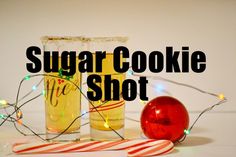 there is a candy cane next to two glasses with sugar cookie shots in them and the words sugar cookie shot above it