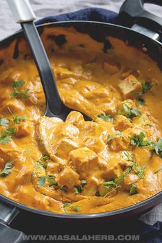 a skillet filled with chicken curry and garnished with cilantro