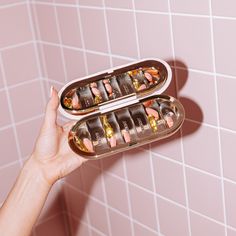 a person holding two trays of food in front of a pink tiled bathroom wall