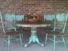 an old table with four chairs and a basket full of flowers sitting on top of it