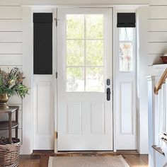 a white front door with black shutters on the side and an entry mat rug