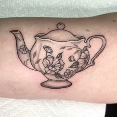 a black and white photo of a teapot with flowers on it