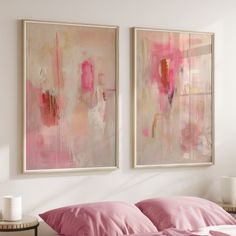 two paintings hang on the wall above a bed with pink sheets and pillows, along with a side table