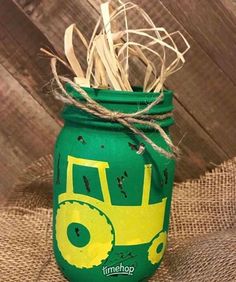 a green mason jar with a yellow tractor painted on it and twine in the top