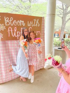 two women standing next to each other in front of a sign that says bloom with hope