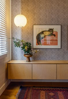 a room with a painting and some plants on the sideboard in front of it