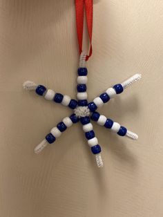 an ornament made out of toothbrushes hanging from a red and white ribbon