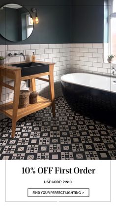 a bathroom with black and white tiles on the floor, sink and bathtub in front of a round mirror