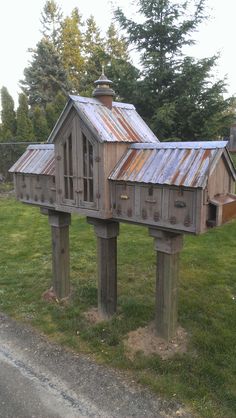 a bird house made out of old windows and sidings in the grass with trees in the background