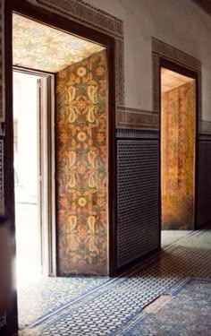 an open door leading to another room with tile flooring and wallpaper on the walls