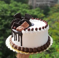 a hand holding a cake with chocolate decorations