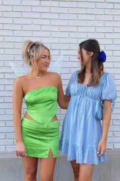 two women dressed in fairy costumes standing next to each other, one wearing a blue and green dress