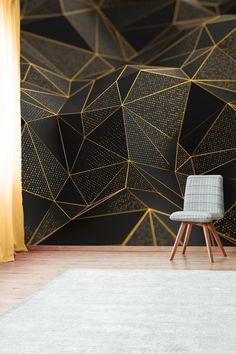 a chair sitting in front of a black and gold geometric wallpaper with lines on it