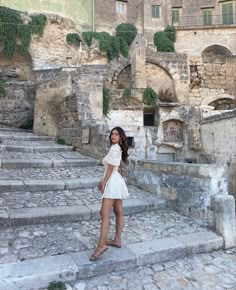 a woman is standing on some steps in front of an old building with stone stairs