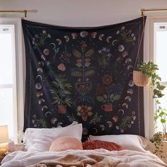 a large tapestry hanging over a bed with pillows and blankets on it's sides