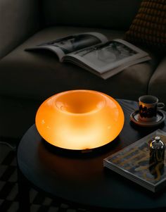 a table with a lamp on top of it next to a book and coffee cup