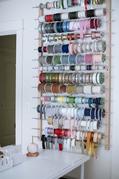 there is a rack with many spools of thread hanging on it's wall