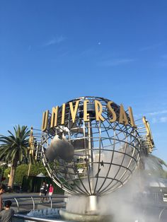 people are standing in front of the universal studios sign with steam coming out of it