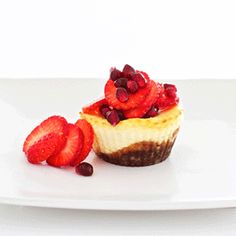 a cupcake topped with strawberries on top of a white table next to berries