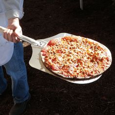 a person holding a pizza on a spatula