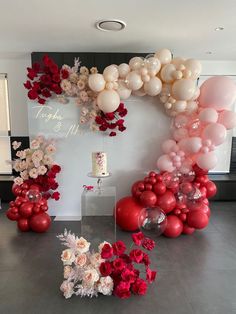 balloons and flowers are arranged on the floor in front of a wall with an arch