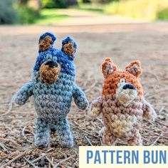 two crocheted teddy bears standing next to each other on top of dry grass