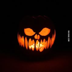 a carved pumpkin with glowing eyes and fangs on it's face in the dark