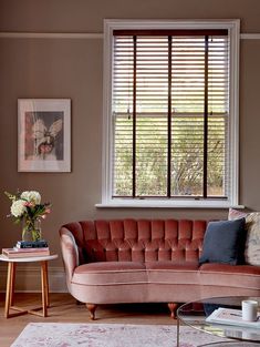 a living room filled with furniture and a large window covered in wooden slatted blinds