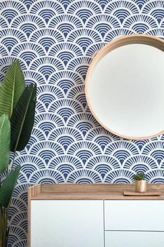 a round mirror sitting on top of a dresser next to a plant