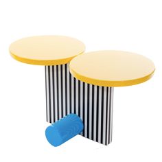 two round tables with yellow tops and black and white stripes on the sides, one has a blue plastic object next to it