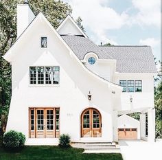 a large white house with two wooden doors on the front and one door open to let in light