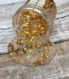 a glass jar filled with yellow glitter on top of a wooden table