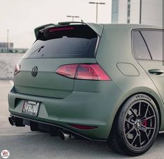 the back end of a green car parked in a parking lot