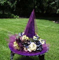 a purple hat sitting on top of a wooden bench in the grass with flowers around it