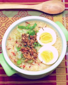 a bowl of oatmeal with two hard boiled eggs and green onions on top