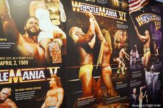 several large posters are on the wall in front of each other, including wrestlers and women