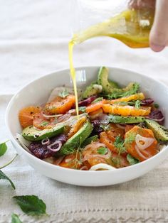 someone pouring dressing into a bowl filled with vegetables