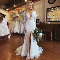 a woman in a white wedding dress standing on a wooden floor next to some dresses