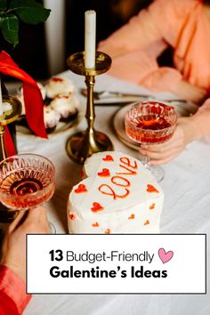 a table topped with a heart shaped cake next to two candles and plates filled with cupcakes