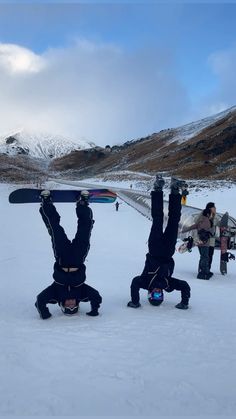 three snowboarders doing handstands in the snow with their boards on their heads