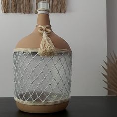 a bottle that is sitting on a table next to a plant and some tassels