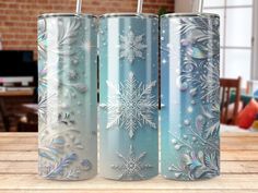 three snowflaked tumblers sitting on top of a wooden table