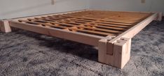 a wooden bed frame sitting on top of a carpeted floor next to a wall