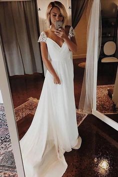 a woman taking a selfie in front of a mirror wearing a white wedding dress