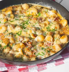 a skillet filled with food sitting on top of a red and white checkered table cloth