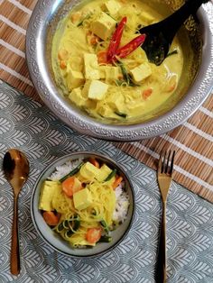 a bowl filled with tofu and rice next to a fork, knife and spoon